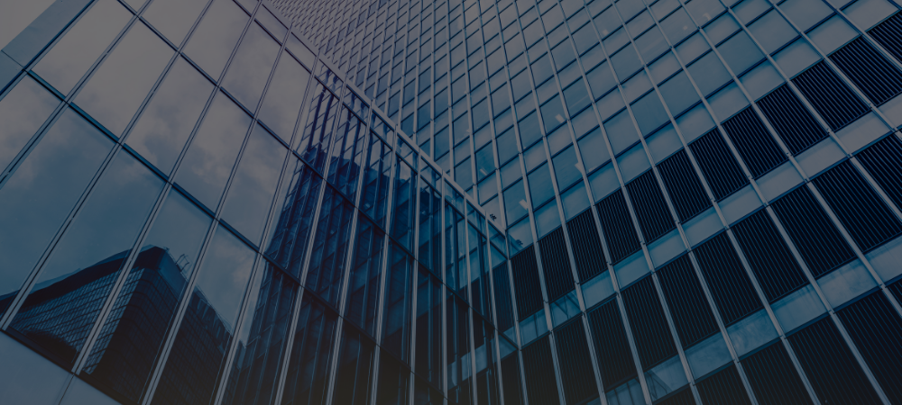 Reflective glass facade of a modern skyscraper with geometric patterns and lines.