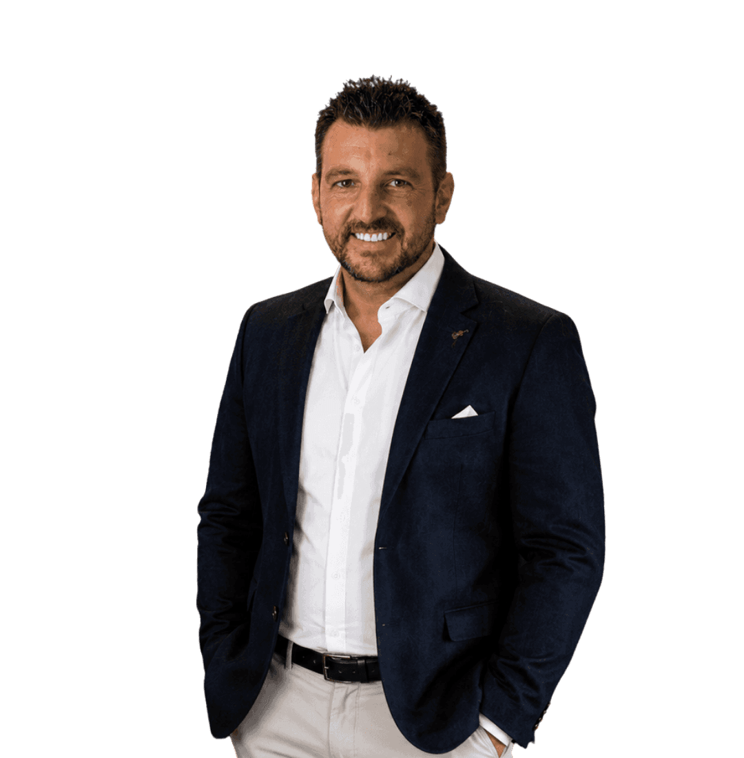 Smiling male hypnotherapy practitioner in a navy suit and white shirt, standing with his hands in his pockets